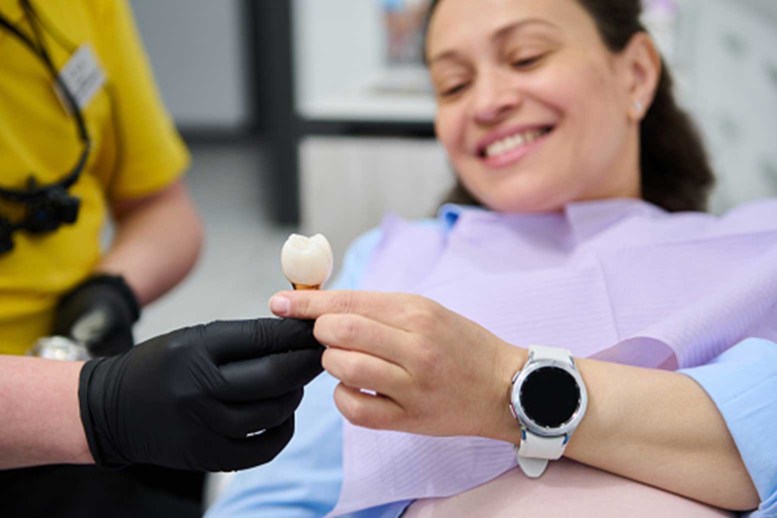 Dental implant patient holding tooth model at South Ogden & Kaysville, UT dental office.