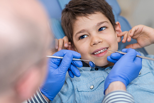 Dentist doing regular dental check-up to little boy.